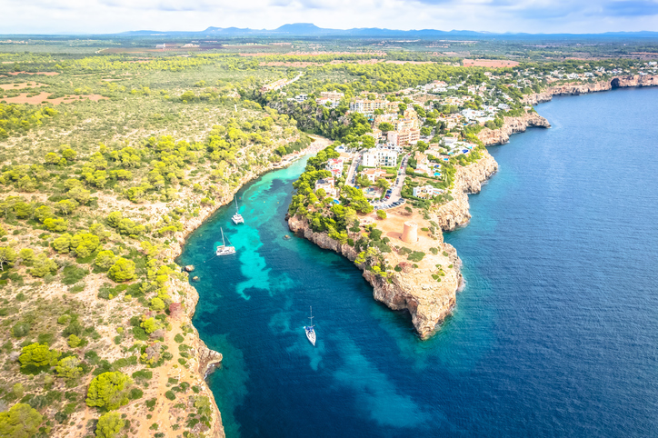 Luftbild von Cala Pi mit tief eingeschnittener Bucht, türkisblauem Wasser, Felsen und umliegenden Häusern.