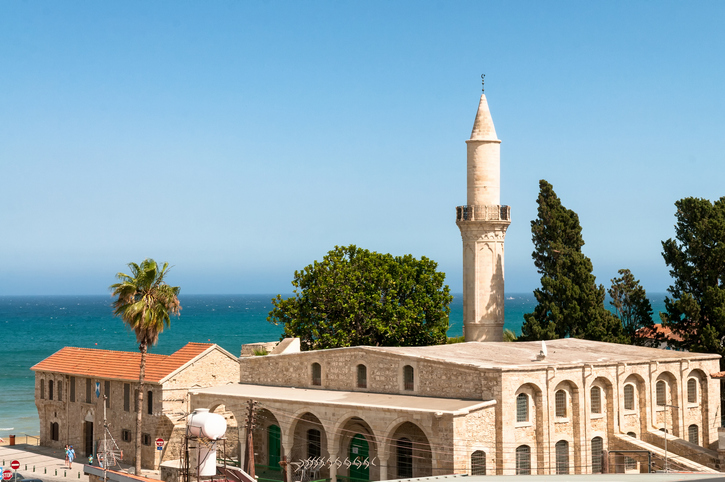 Steinernes Gebäude mit schlankem Minarett und Meer im Hintergrund in Larnaka