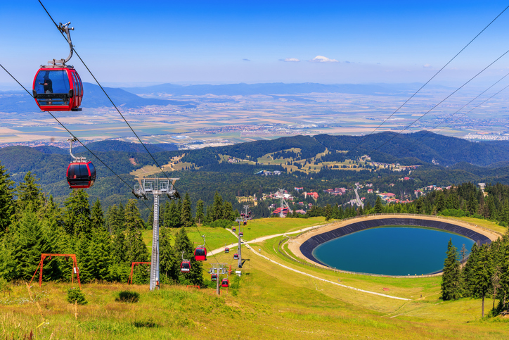 Rote Gondeln über grünen Berghängen bei Brașov in Rumänien