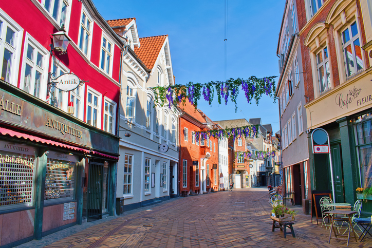 Eine ruhige Gasse mit farbigen Häusern, kleinen Geschäften und Blumenschmuck liegt in Odense.