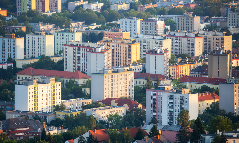 Blick auf Wohnhäuser und moderne Stadtviertel in Pécs im warmen Abendlicht.