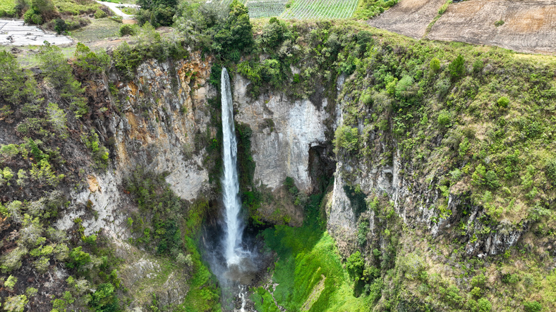 Ein hoher Wasserfall stürzt in eine grüne Schlucht in der Umgebung von Medan.