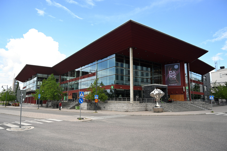 Modernes Glasgebäude in Luleå mit breitem Dach, großen Fenstern und städtischer Umgebung.