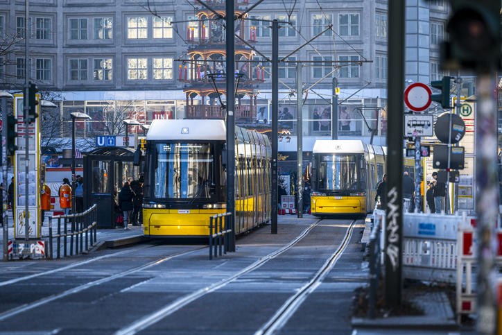 Zwei gelbe Straßenbahnen fahren durch eine belebte Straße im Zentrum von Berlin.