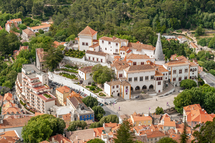Ein großer historischer Gebäudekomplex liegt zwischen Bäumen und Häusern im Zentrum von Sintra.