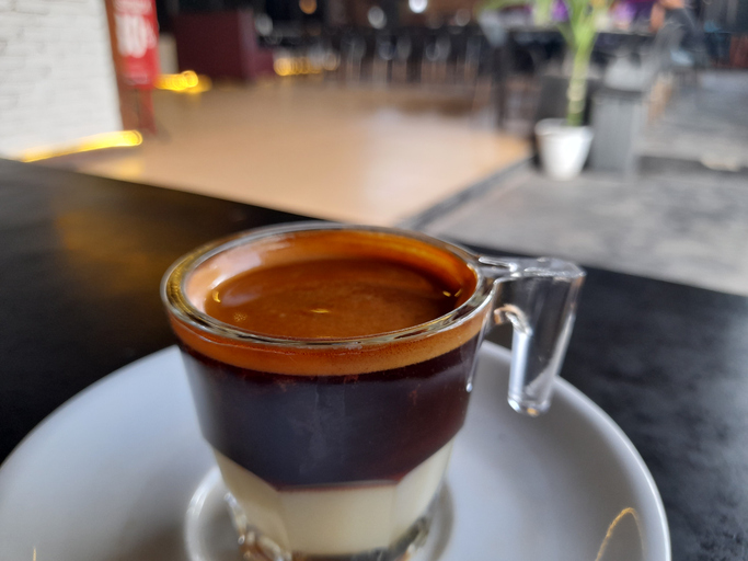 Ein Glas Kaffee mit cremiger Schicht steht auf einem Teller in einem Café in Medan.
