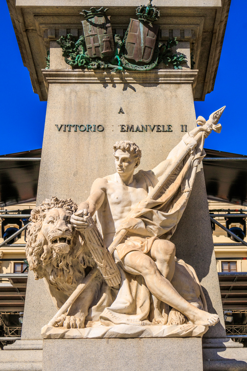 Steinernes Denkmal mit männlicher Figur und Löwenstatue auf einem Platz in Sassari