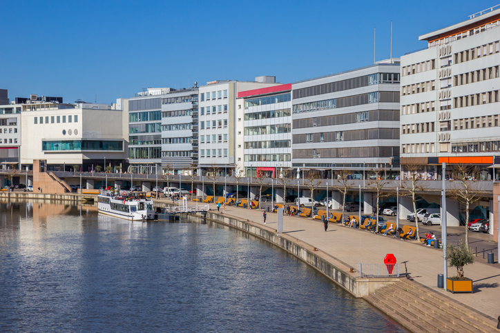 Blick auf die Uferpromenade in Saarbrücken mit modernen Gebäuden, Flussufer und Spazierbereich.