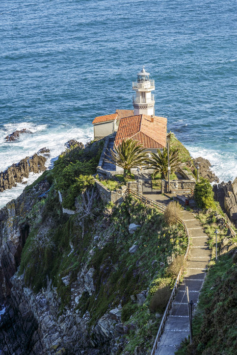 Ein kleiner Leuchtturm steht auf einer felsigen Klippe über dem Meer nahe Cudillero.