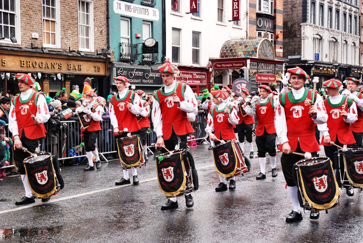 Eine Gruppe von Trommlern in roten und weißen Kostümen zieht bei einer Parade durch eine Straße in Dublin.