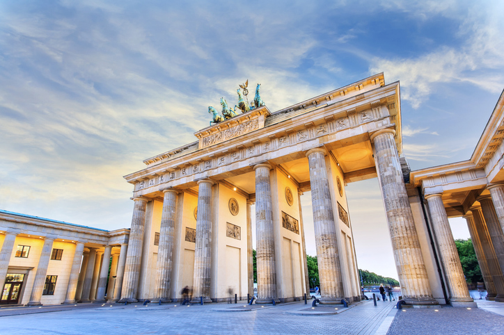 Das Brandenburger Tor in Berlin steht mit seinen Säulen und der Quadriga unter hellem Himmel.