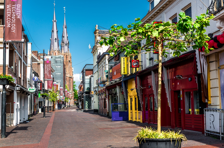 Fußgängerzone in Eindhoven mit bunten Fassaden und der Sint-Catharinakirche im Hintergrund.