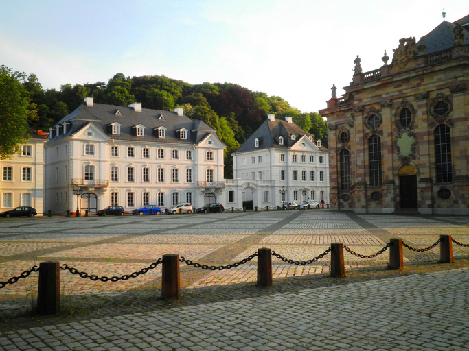 Großer gepflasterter Platz in Saarbrücken mit hellen historischen Gebäuden und der barocken Ludwigskirche.