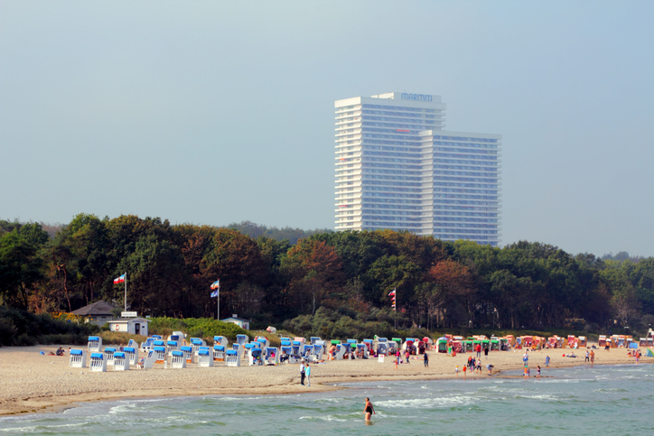 Sandstrand mit Strandkörben und großem Hotelgebäude im Hintergrund in Timmendorfer Strand.