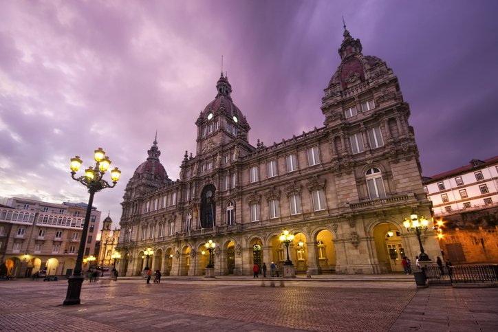 Prächtiges historisches Gebäude auf einem beleuchteten Platz in A Coruña bei Abenddämmerung
