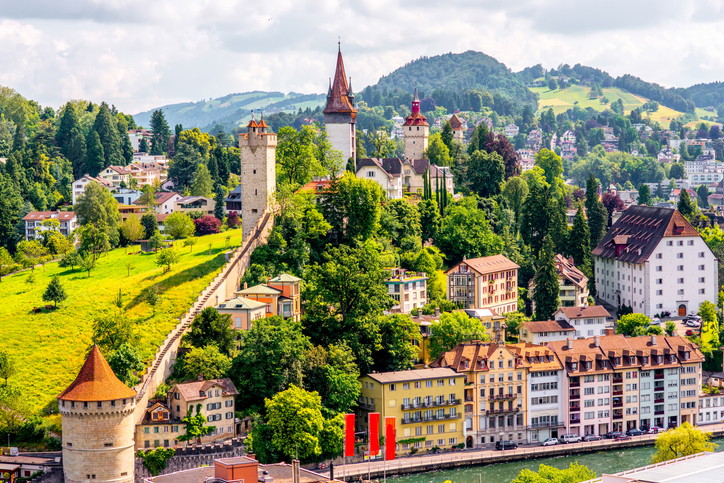 Die Museggmauer mit Türmen erhebt sich über Luzern und grünen Hängen.