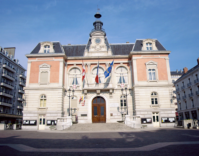 Prächtiges Rathaus mit Uhrturm und französischen Fahnen auf einem Platz in Chambéry