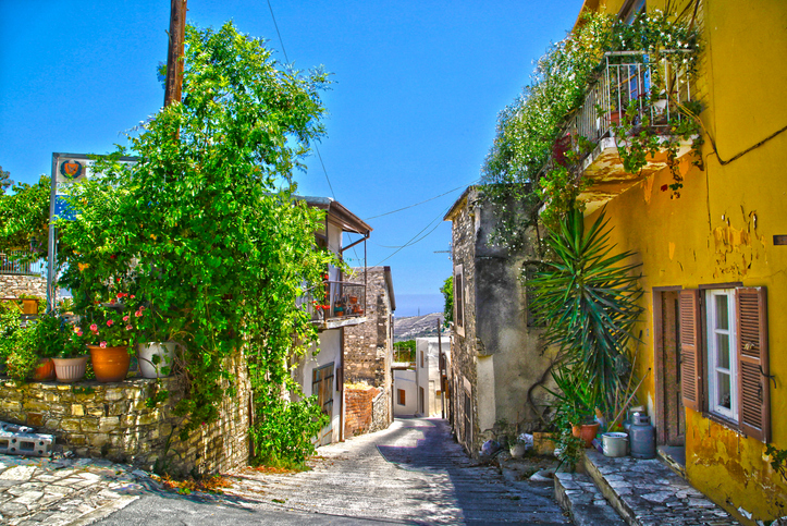 Enge Straße mit Natursteinhäusern, Pflanzen und sonniger Atmosphäre in einem historischen Viertel bei Larnaka