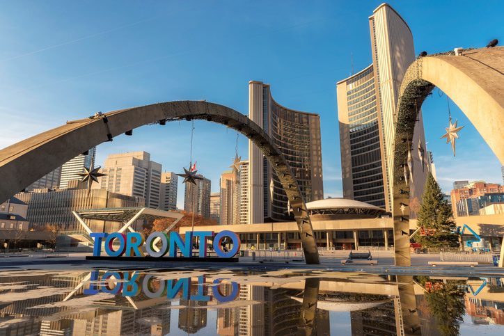 Nathan Phillips Square in Toronto mit Toronto-Schriftzug, Bögen und dem Rathaus im Hintergrund.