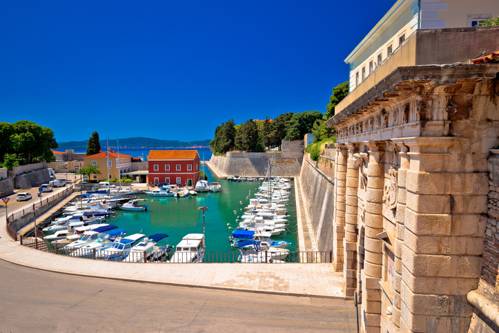 Kleine Boote liegen im Foša-Hafen von Zadar neben historischen Mauern und klarem Wasser.