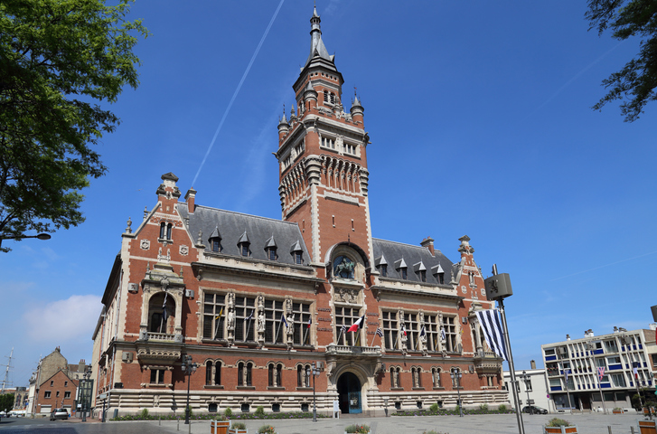 Das historische Rathaus von Dunkerque mit seinem markanten Turm unter blauem Himmel.