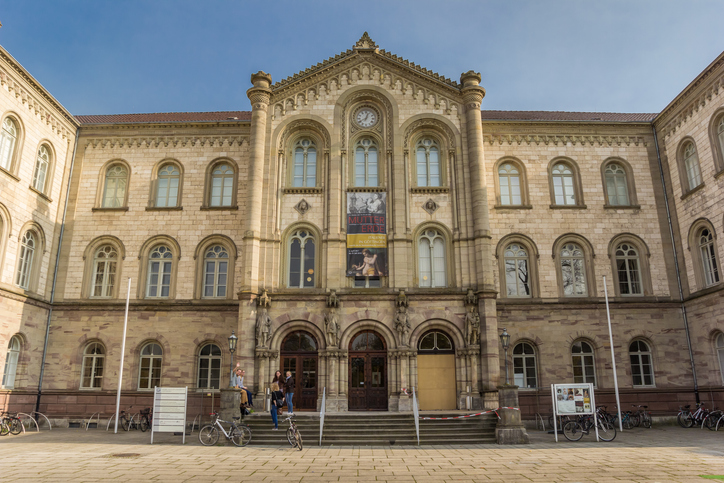 Ein großes historisches Gebäude der Universität Göttingen mit steinerner Fassade und Fahrrädern davor.