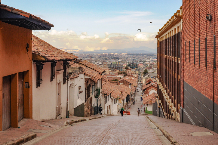 Steile Straße mit kolonialen Häusern und Blick über Bogotá