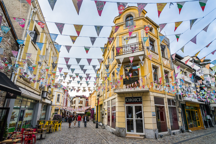 Kopfsteinpflasterstraße in Plowdiw mit bunten Wimpeln, historischen Fassaden und kleinen Lokalen.