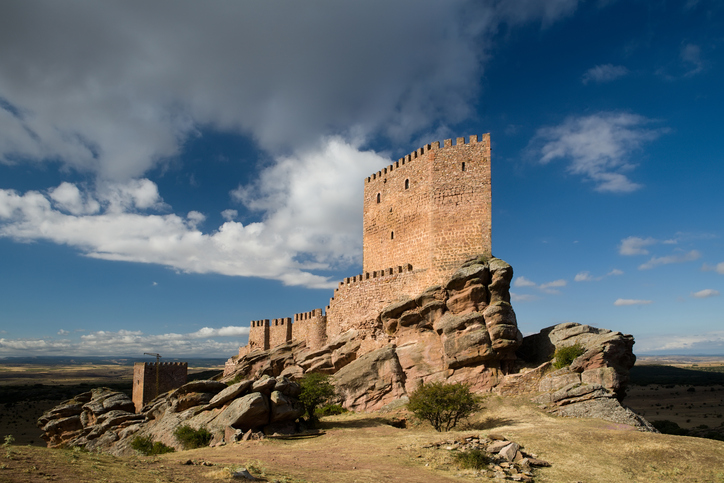 Mittelalterliche Burg auf einem felsigen Hügel unter blauem Himmel in der Region Badajoz