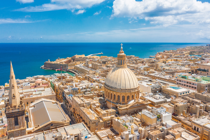 Luftaufnahme von Valletta in Malta mit großer Kuppel, Küstenlinie, dicht bebauter Altstadt und weitläufigem Blick auf das Meer.