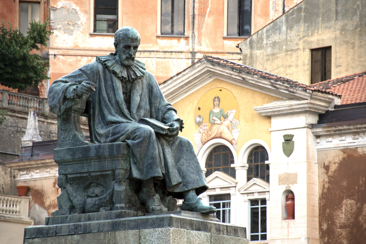 Bronzestatue eines sitzenden Gelehrten vor einem historischen Gebäude in Cosenza