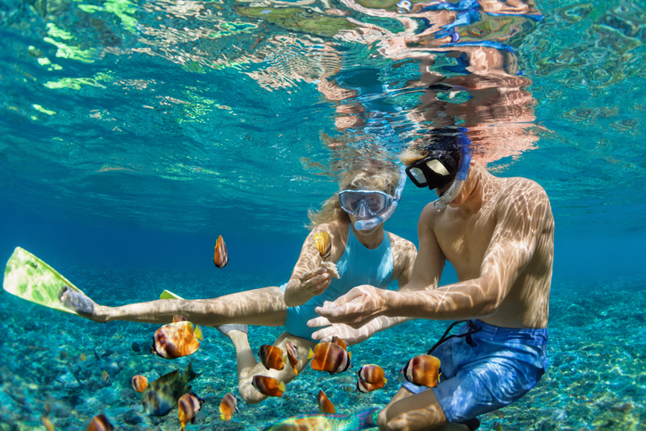 Zwei Menschen mit Schnorchelmasken beobachten tropische Fische unter Wasser in einem klaren Meer