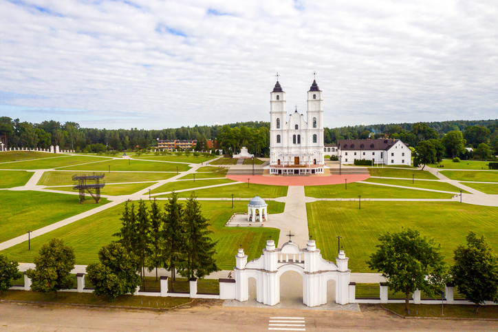 Katholische Basilika im Dorf Aglona in Latgale, Lettland, mit zwei weißen Türmen, weitläufigem Vorplatz und gepflegter Parkanlage.