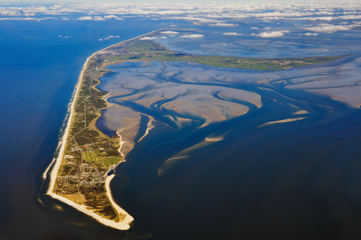 Luftbild von Sylt mit langgezogener Insel, Sandstränden, Wattflächen und schmaler Landzunge zwischen Nordsee und Wattenmeer.
