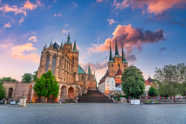 Erfurter Dom und Severikirche am Domplatz in warmem Abendlicht mit breiter Treppe und dramatischem Himmel.