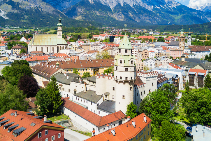 Blick auf die Burg Hasegg in Hall in Tirol mit Münzerturm, Altstadt und Bergen im Hintergrund.