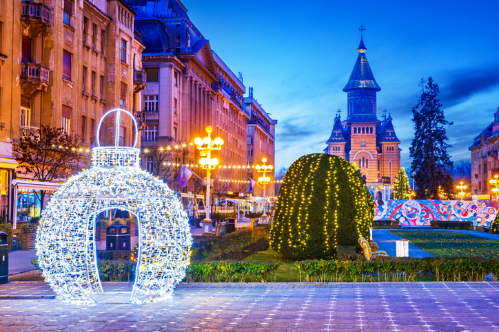 Beleuchteter Platz in Timișoara mit Weihnachtsdekoration und Kathedrale im Hintergrund