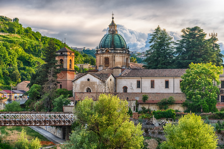 Alte Kirche mit großer Kuppel, Glockenturm und Brücke in der grünen Flusslandschaft von Cosenza