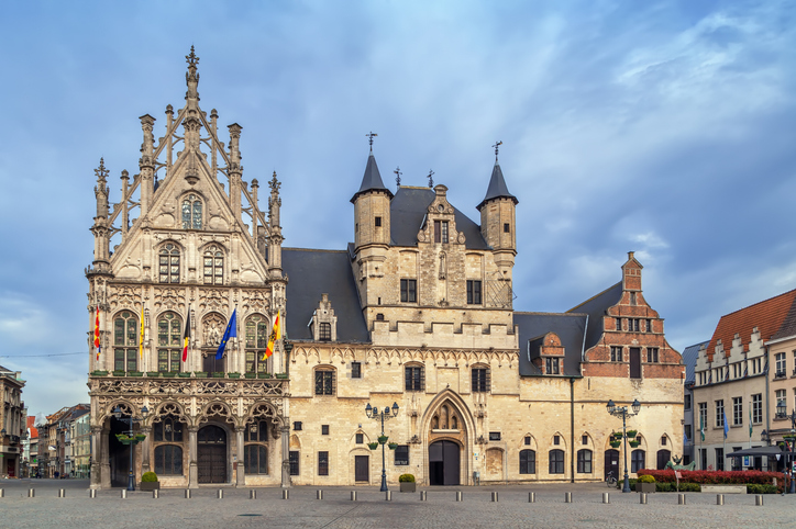 Prächtiges historisches Rathaus von Mechelen mit gotischer Fassade, Türmen und Fahnen am Grote Markt.