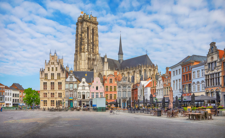 Großer Marktplatz in Mechelen mit farbenfrohen historischen Giebelhäusern und dem hohen Turm der St.-Rumbold-Kathedrale.