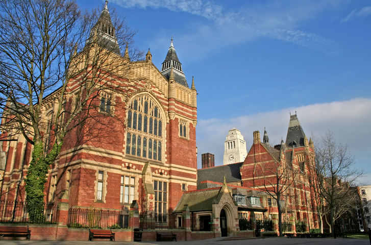 Historisches Universitätsgebäude in Leeds mit roter Backsteinfassade, großen gotischen Fenstern, Türmen und dekorativen Steinelementen.