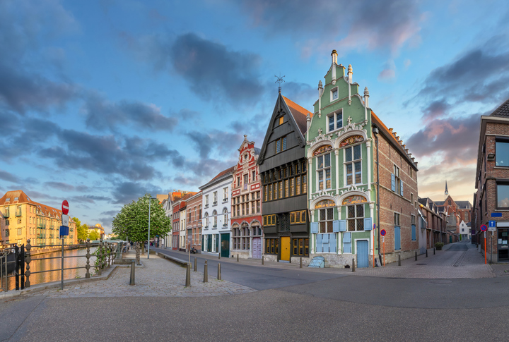 Historische Giebelhäuser in Mechelen mit kunstvoll gestalteten Fassaden an einer ruhigen Straße nahe einem Kanal.