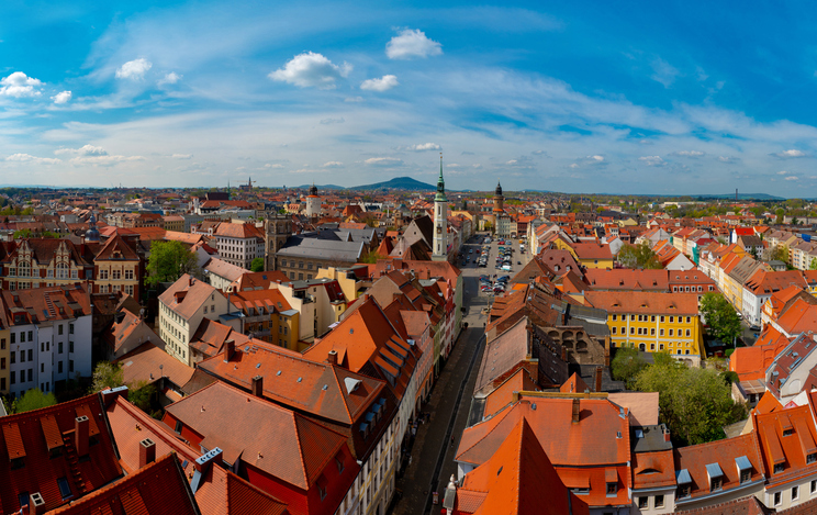 Luftaufnahme von Görlitz mit historischer Altstadt, roten Ziegeldächern, Marktplatz und dicht bebauten Straßenzügen unter blauem Himmel.