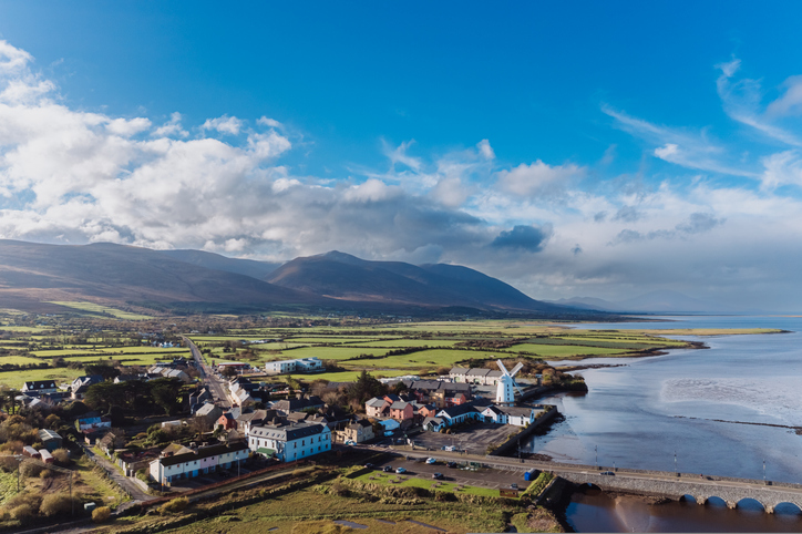 Luftaufnahme von Dingle mit Küste, Häusern und Bergen im Hintergrund