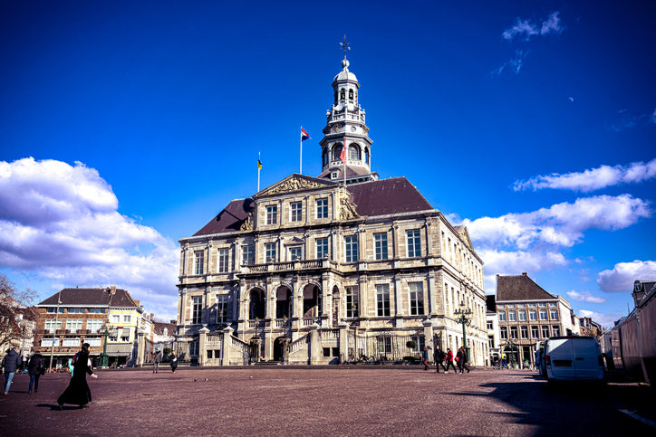 Historisches Rathaus am Marktplatz von Maastricht mit repräsentativer Fassade, hohem Turm und weitem Platz unter blauem Himmel.