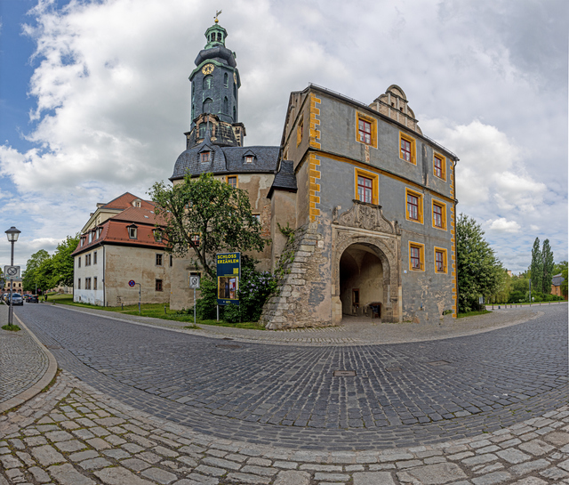 Ein altes Torhaus mit Rundbogen und dunklem Turm steht an einer gepflasterten Straße in Weimar.