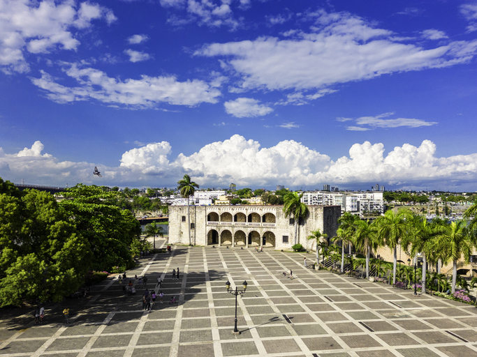 Großer Platz mit historischem Gebäude und Palmen in Santo Domingo