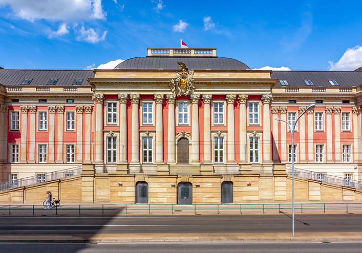 Historische Fassade des Brandenburger Landtags im rekonstruierten Potsdamer Stadtschloss mit roten Wandflächen, Säulen und reich verziertem Portal.