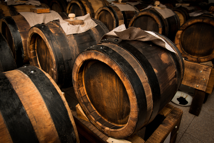 Traditionelle Holzfässer zur Reifung von Balsamico-Essig aus Modena in einem dunklen Lagerraum.
