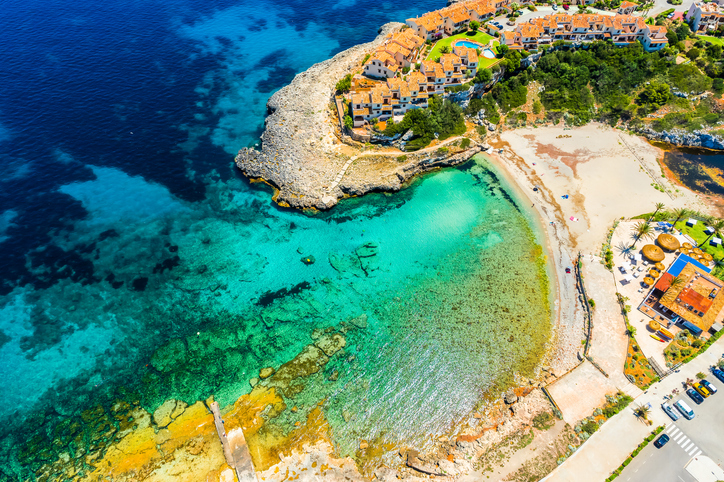 Luftaufnahme der Bucht von Cala Murada mit hellem Strand, felsiger Küste und türkisfarbenem Meer